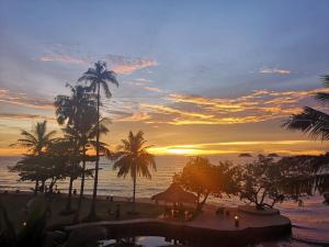 einen Sonnenuntergang über einem Strand mit Palmen und dem Meer in der Unterkunft Koh Chang Bailan Beach Resort in Ko Chang