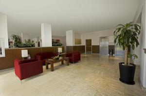 a lobby with red furniture and a potted plant at One Queretaro Plaza Galerias in Querétaro