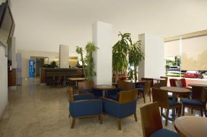 a restaurant with blue chairs and tables and tables at One Queretaro Plaza Galerias in Querétaro