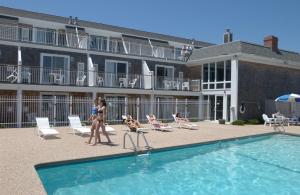 eine Gruppe von Menschen, die um ein Schwimmbecken herumlaufen in der Unterkunft InnSeason Resorts Captain's Quarters in Falmouth