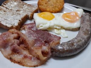 un plato de desayuno con salchichas y tostadas en Baron's Palace, en Oudtshoorn