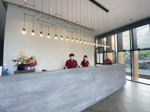 zwei Personen in einer Lobby, die Masken tragen in der Unterkunft M2 Hotel Waterside in Phayao