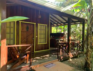 Cabaña de madera con porche con mesa y sillas en Cabinas Coco Lindo en Ojochal