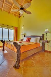 a bedroom with a large bed with a ceiling fan at Laru Beya Resort in Placencia