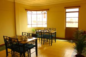 uma sala de jantar com mesas, cadeiras e janelas em Check Inn Bed and Breakfast em Cuenca
