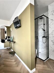 a bathroom with a shower and a television on the wall at Valkenhof in Valkenburg