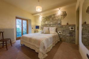 - une chambre avec un mur en pierre et un lit dans l'établissement Al Poderuzzo Private Villa with jacuzzi and garden, à Castelnuovo deʼ Sabbioni