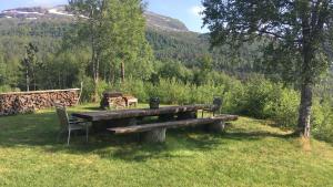 a wooden picnic table with two chairs in a field at Voss Lodge Rongastovo in Vossevangen +13 photos