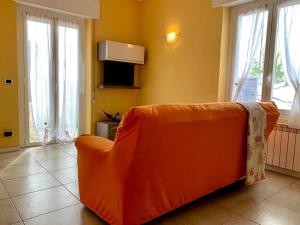 un sofá naranja en una sala de estar con ventanas en La Posidonia sul mare, en Santo Stefano al Mare