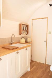 a kitchen with white cabinets and a sink at Orchard Farm Luxury Glamping in Glastonbury
