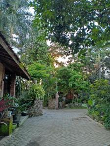 a brick walkway with trees and plants on it at Bata Merah Homestay in Banyuwangi