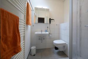 a white bathroom with a sink and a toilet at Ferienhaus Kleine Oase in Varel +14 photos