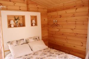 a bedroom with a bed in a wooden wall at CHALET ESPRIT ZEN et NATURE AVEC SPA in Saint-Hilaire-de-Riez