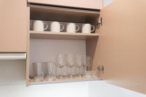 a row of wine glasses on a shelf in a kitchen at Scandinavian apartment Elegant in Lviv