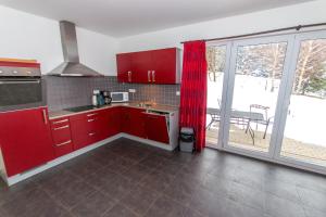 kuchnia z czerwonymi szafkami i dużym oknem w obiekcie Villa Slupečná w mieście Lipno nad Vltavou
