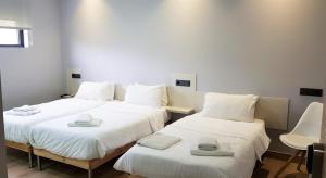 2 Betten in einem Zimmer mit weißer Bettwäsche und Handtüchern darauf in der Unterkunft Pensión LO in O Pedrouzo