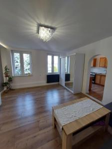 an empty living room with a table and windows at Nowoczesny apartament w zacisznym sercu Torunia. in Toruń