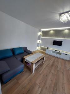 a living room with a blue couch and a table at Nowoczesny apartament w zacisznym sercu Torunia. in Toruń
