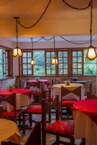 uma sala de jantar com mesas, cadeiras e janelas em Hotel Pousada Arcádia Mineira em Ouro Preto