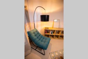 a living room with a blue chair and a desk at La veilleuse - Appartement au cœur du centre ville in Limoges