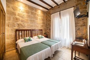 a bedroom with two beds and a stone wall at Hostal Tres Molins in Jesus Pobre