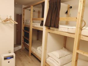 a room with three bunk beds with towels at Guest House Yadomaru in Osaka