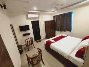Habitación de hotel con 2 camas y TV en Kings Court Guest Inn, en Nellore