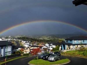 een regenboog in de lucht over een straat met auto's bij The Rise BNB - Executive Ensuite in Auckland