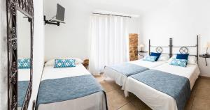 two beds in a room with blue and white at Hostal Tres Molins in Jesus Pobre