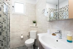 a white bathroom with a toilet and a sink at Lia's Home Two in Mantoúkion +32 photos