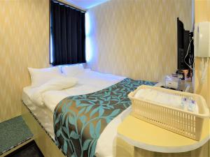 Piccola camera d'albergo con letto e tavolo di 西船橋駅前 HOTEL a Funabashi