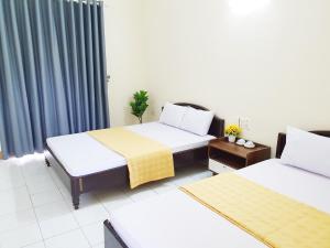 a hotel room with two beds and a window at Khách Sạn Tuấn Thảo Cửa Lò in Cửa Lô