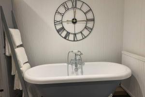 a bathroom with a sink and a clock on the wall at Clock Cottage Self contained Rutland Rural Retreat in Manton +11 photos