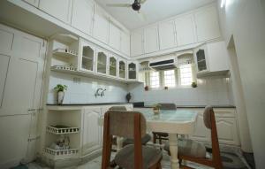 a kitchen with white cabinets and a table and chairs at Adams Cottage Kochi in Cochin