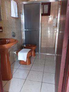 uma casa de banho com 2 WC, um lavatório e um chuveiro em Pousada Caminho do Mar em Torres