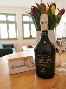 a bottle of wine on a table with a vase of flowers at Kornmühle Appartment Gabi in Mellenthin