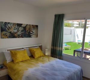 a bedroom with a bed with yellow pillows and a window at Villa Orquidea with private garden in Playa del Ingles