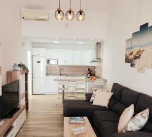 a living room with a couch and a kitchen at Villa Orquidea with private garden in Playa del Ingles