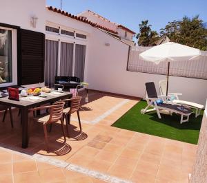 een terras met een tafel, stoelen en een parasol bij Villa Orquidea with private garden in Playa del Inglés
