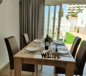 a dining room table with a bottle of wine on it at Villa Orquidea with private garden in Playa del Ingles