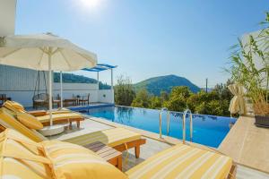 a swimming pool with yellow chairs and an umbrella at VillA Esin in Kaş