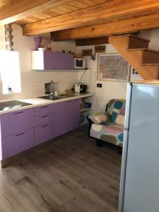 a kitchen with purple cabinets and a couch at Chez Sylvie Vda-Issogne-001 in Issogne