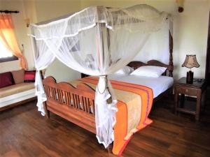 a bed with a canopy on top of it at Lanka Beach Bungalows in Tangalle