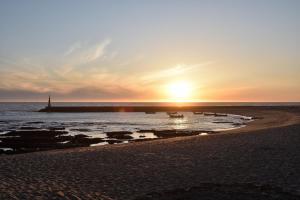 a sunset on the beach with boats in the water at Retiro da Praia da Aguda in Arcozelo