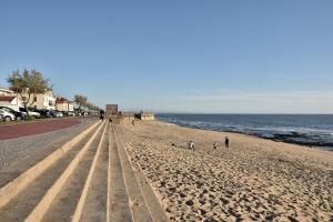 a beach with people walking on the sand and the ocean at Retiro da Praia da Aguda in Arcozelo