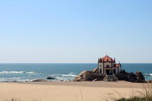 a lighthouse sitting on the beach next to the ocean at Retiro da Praia da Aguda in Arcozelo
