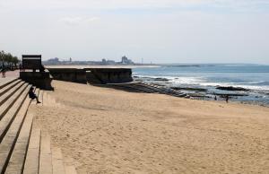 a sandy beach with people walking on it next to the ocean at Retiro da Praia da Aguda in Arcozelo