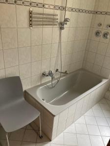 een bad in een badkamer met een stoel bij Ferienwohnung Tapetenwechsel -Balkon- in Dresden