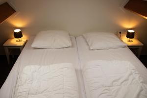 1 cama blanca grande con 2 almohadas y 2 lámparas en Koetsementen appartementen, en Domburg