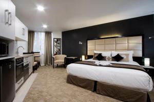 a hotel room with a large bed and a kitchen at VR Queen Street Hotel & Suites in Auckland